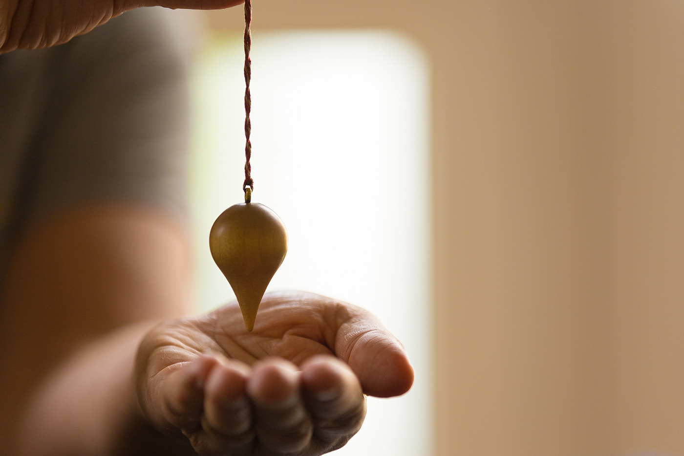 Medizinische Fotografie Rosenheim, Praxisfotografie, Fotos Naturheilkundepraxis, Fotografie Praxis für Naturheilkunde, Praxisportrait Nahaufnahme von Händen mit Pendel in einer Naturheilkundepraxis, Praxisfoto, Praxis Heilpraktikerin Ulrike Stadler
